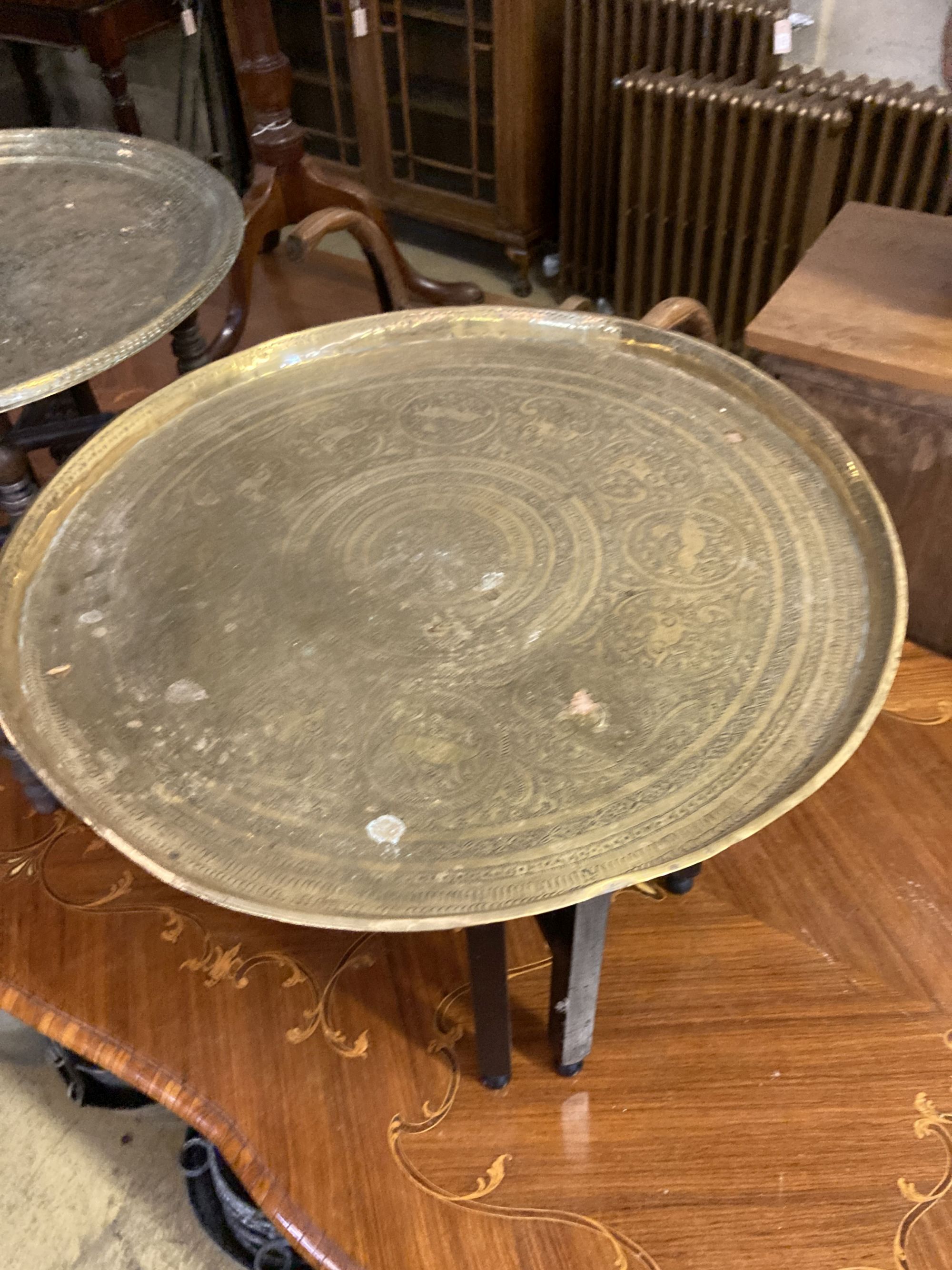 Two Benares engraved circular tray top tables, larger 59cm diameter, 53cm high